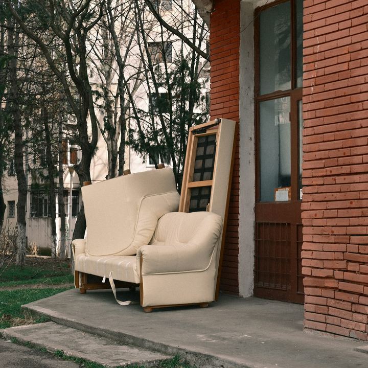 Old sofa and armchair left outside a brick building