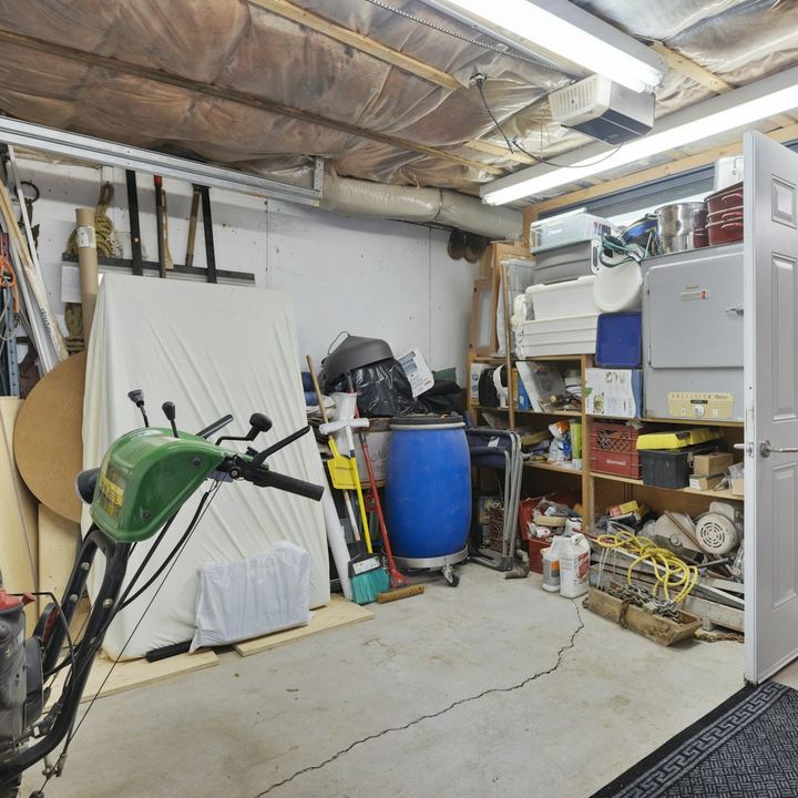 Cluttered garage packed with shelves, tools, and storage bins